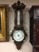 A late Victorian carved oak aneroid barometer