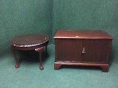 A circular mahogany coffee table on claw and ball feet plus a double door cabinet