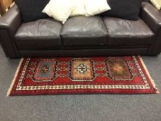 A Persian fringed rug on red ground,
