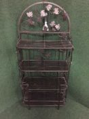 A metal four tier stand with leaf decoration