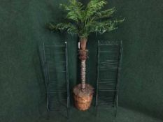 An artificial palm plant in pot and a pair of folding metal stands