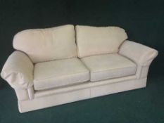 A contemporary two seater settee in a sand coloured fabric