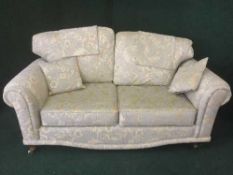 A two seater settee and matching armchair in a green and gold floral print