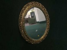 A decorative oval gilt framed mirror