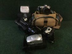 A box containing assorted cameras and camera equipment including Canon digital video camcorder,