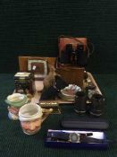 A tray of binoculars in case, character jugs, Maling dish, miniature chest, paperweights, pens,