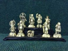 A group of Oriental resin figures on wooden plinth