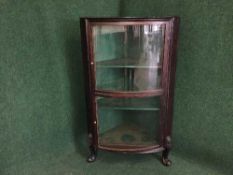 A mahogany glazed bowfronted corner cabinet