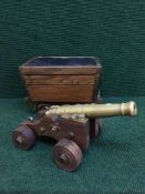 A brass cannon on wooden trolley and a sewing box modelled as a wooden cart