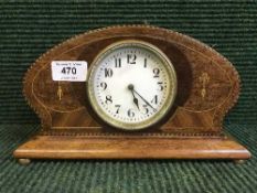 An inlaid oak mantel clock on brass feet