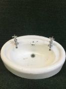 A mid 20th century oval wash basin with taps