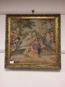 A gilt framed tapestry depicting figures by a wall