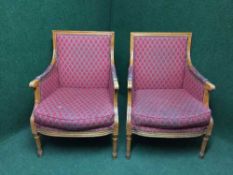 A pair of Victorian style armchairs upholstered in red fabric on reeded legs