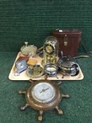 A tray of desk and travel clocks, clock under shade, ships wheel barometer, plated ware,