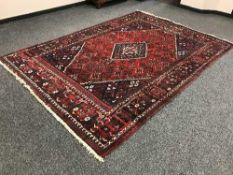 A fringed Persian carpet on red ground