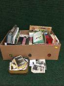A box of books, vintage postcards and monochrome photographs,