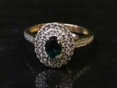 A diamond cluster ring with green central stone,
