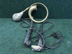 A tray of two bull whips and a brass car horn