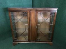 A glazed door bookcase on bracket feet