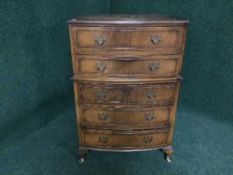 A walnut bow-fronted five drawer chest