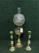 An early 20th century brass and glass oil lamp and a pair of brass candlesticks