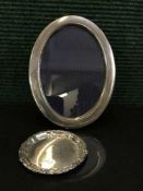 A oval silver photograph frame together with a pin dish