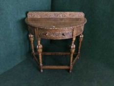 A carved oak d-shaped hall table fitted with a drawer