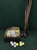 A bundle of hickory shafted golf clubs together with a box of golf balls