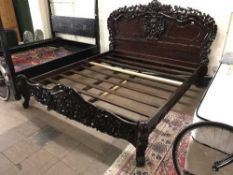 A heavily carved mahogany 6' bed frame