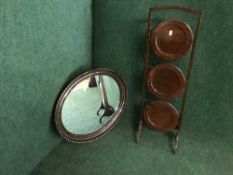 A folding cake stand and an oval framed mirror