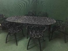 A large oval wrought iron garden table with six armchairs