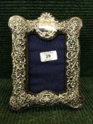 An early twentieth century white metal easel picture framed with embossed decorations,