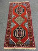 A Persian wool fringed rug on red ground