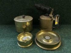 A tray of brass blow torch, two brass shell case ashtrays and a 2007 commemorative £5 coin.