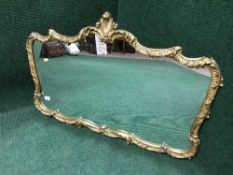 An ornate gilt metal framed overmantle mirror