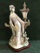 A Lladro figure - Geisha standing by a garden and lamp, standing upon a plinth base.