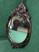 A large oval ornate mahogany framed mirror