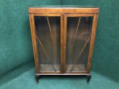 A mahogany double door display cabinet on pad feet