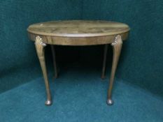 An oval walnut occasional table on pad feet