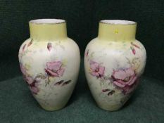 A pair of antique pottery hand painted vases depicting flowers