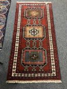 A fringed Persian wool rug on red ground with medallion border