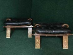 A pair of brass inlaid leather upholstered camel stools