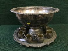 A large plated punch bowl with tray and eleven goblets
