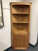 An Ercol light elm corner cabinet
