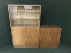 A mid 20th century sliding door bookcase and matching double door cupboard