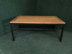 A contemporary teak coffee table on a wrought iron base