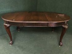 A mahogany wind-out table on claw and ball feet with handle