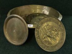 A large circular brass bowl containing copper and brass wall plaques