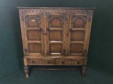 A carved oak triple door sideboard