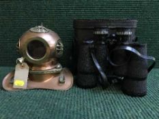 A set of cased Pathescope binoculars and a miniature copper and brass diver's helmet
